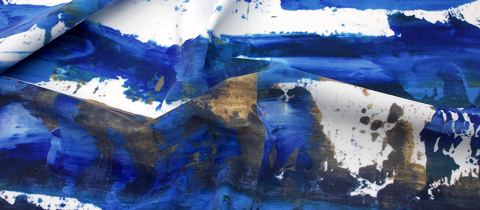 Close-up of richly coloured furnishing velour fabric showing deep blue and gold tones and soft texture