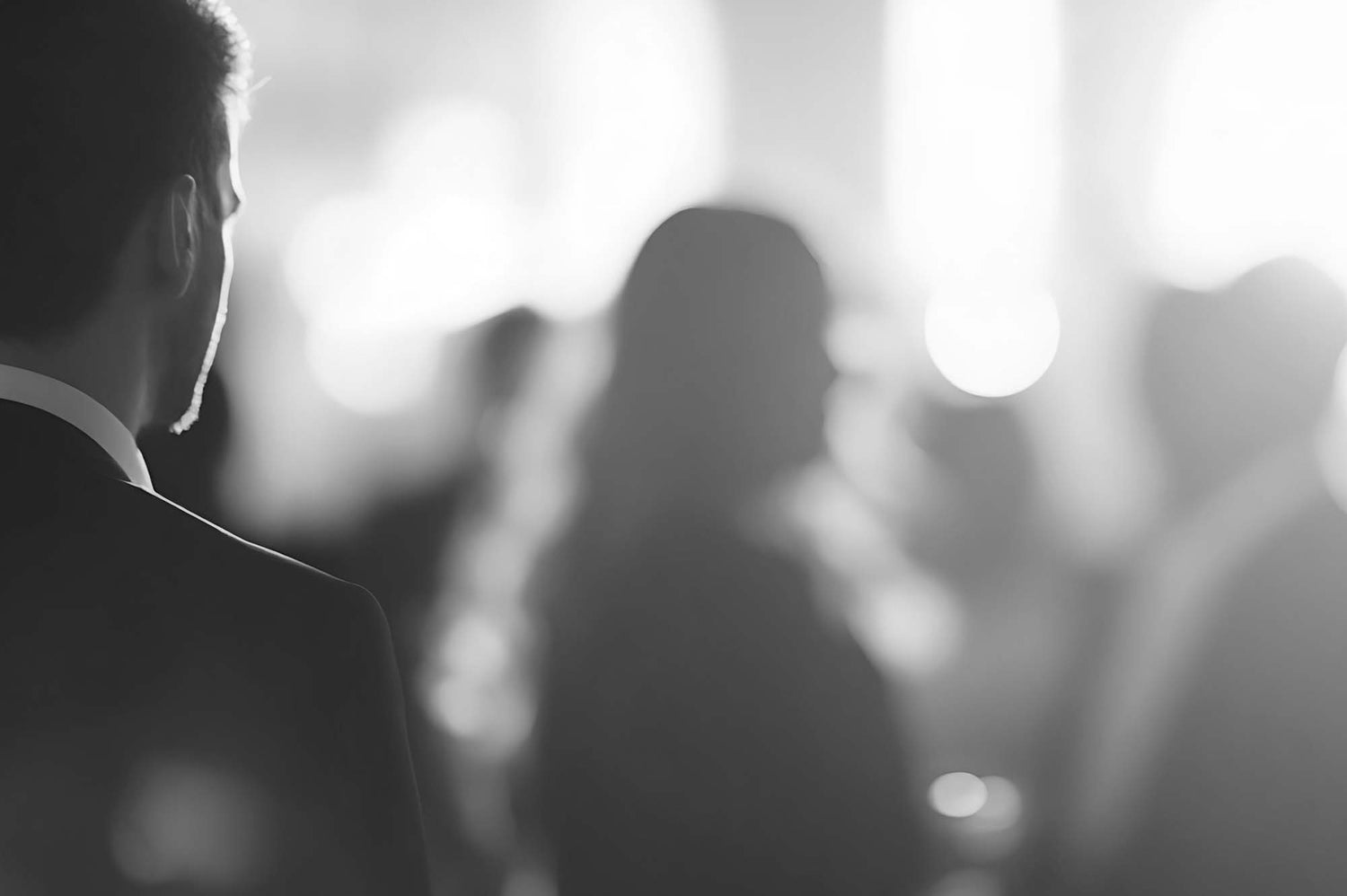 Black and white blurred image of people in formal attire.